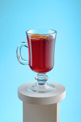 Mulled wine with dried orange, cinnamon sticks and cloves isolated on a blue background. Winter traditional alcoholic hot drink based on wine.