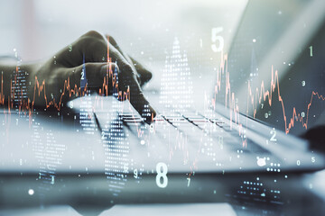 Abstract creative financial graph with hand typing on laptop on background, financial and trading concept. Multiexposure