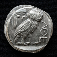Ancient Greek coin showing owl and inscription Athens, vintage metal money isolated on black...