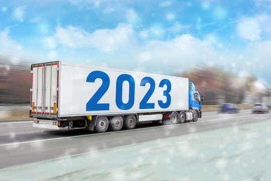 Long trailer trailer with the inscription 2023 new year, the truck rushes along the road during a snowfall snowstorm.