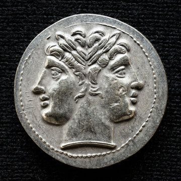 Ancient coin showing two-headed Roman god Janus, 225-214 BC. Vintage money isolated on black background.