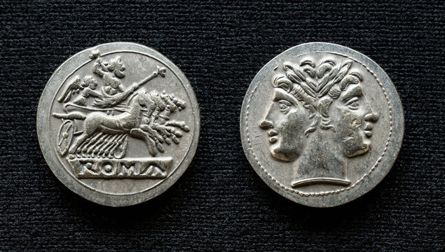 Ancient Roman coin showing Jupiter on horses and two-headed god Janus, 225-214 BC. Vintage silver money isolated on dark background, Texture theme.