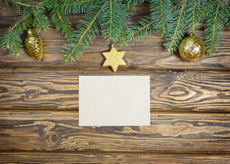 Spruce green branches and a postal envelope on a wooden background. Top view