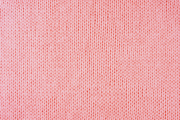 Fototapeta premium Close up background of knitted wool fabric made of viscose yarn. Pastel red color wool knitwear texture. Abstract knitted jersey background. Fabric abstract backdrop, wallpaper