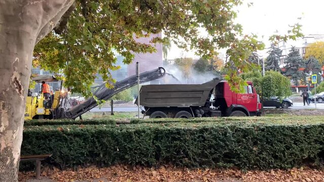 Construction workers are changing asphalt on the road. Workers on construction site with machines on demolition site.