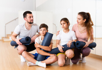 Fototapeta premium Family portrait of kids and parents with yoga mats in gym.