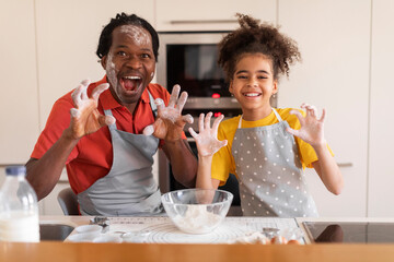 Kitchen Fun. Cheerful Black Father And Daughter Fooling Together While Baking