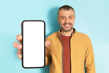 App advertisement. Happy mature man showing big white empty smartphone screen, recommending website or app, mock up