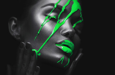 Green Paint smudges drips from the face lips and hand, lipgloss dripping from sexy lips, green liquid drops on beautiful model girl's mouth, make-up. Art design, portrait. Beauty woman makeup close up - 551389173