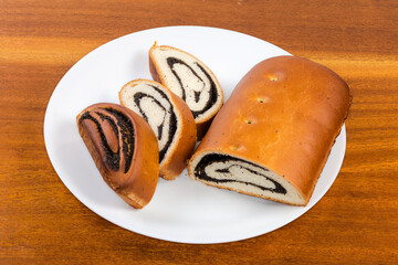 Partly sliced poppy seed roll on the white dish
