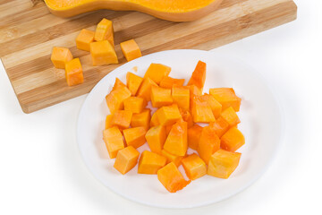 Diced slices of butternut squash on dish against same squash
