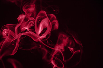 Red puffs of smoke on black background. Color of the year 2023 - Viva Magenta