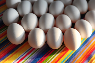 Rows of white eggs arranged on a multicolored striped fabric, evoking themes of traditional food markets, natural products, and vibrant culinary culture