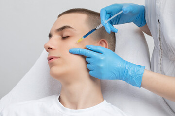 Men's cosmetology. Beautician makes a man a rejuvenation injection procedure of a handsome young...