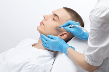 Fototapeta premium A cosmetologist is making the procedure Microdermabrasion of the facial skin in a beauty salon. Cosmetology for men and professional skin care.