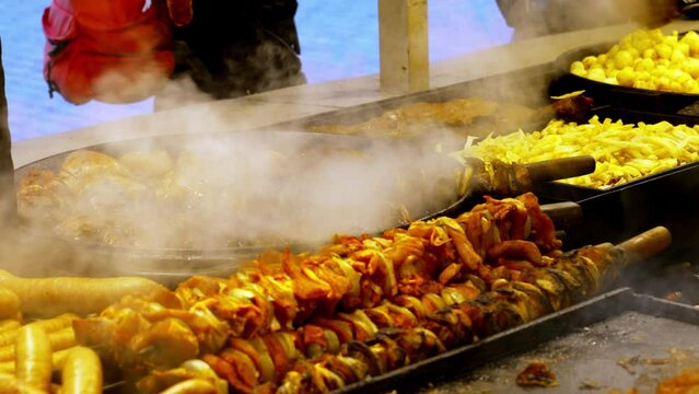 Outdoors, traditional meat dishes are cooked in a large frying pan at a street cafe at the Christmas market in Krakow, Poland. Authentic scene of Polish culinary traditions on the eve of Christmas