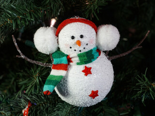 Cute snowman ornament in a red cap and muffler with twigs for arms.