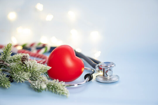 Medical christmas composition with stethoscope and heart close-up and spruce branches in snow on blue background with copy space .
