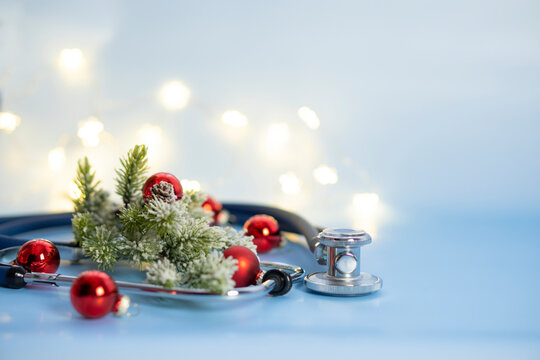 Medical christmas composition with a stethoscope close-up and fir branches in the snow on a blue background with copy space