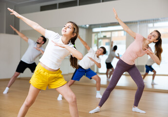 Naklejka na ściany i meble Portrait of tween girl doing exercises during family class in dance center