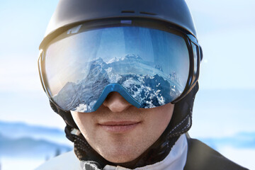 Ski Goggles With The Reflection Of Snowed Mountains. Man On The Background Blue Sky. Winter Sports