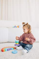 Cute little toddler girl playing at home with eco wooden toys. Happy child cutting vegetables and fruits with toy knife. The child playing educational games.
