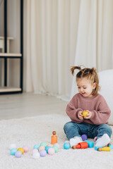 Cute little toddler girl playing at home with eco wooden toys. Happy child cutting vegetables and fruits with toy knife. The child playing educational games.