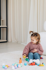 Cute little toddler girl playing at home with eco wooden toys. Happy child cutting vegetables and fruits with toy knife. The child playing educational games.