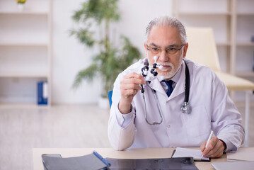 Old male doctor holding molecular model
