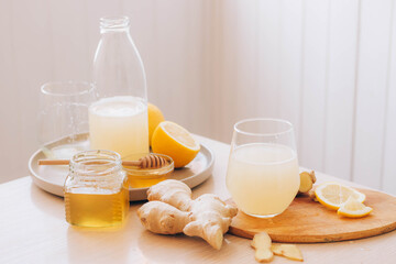 Glass with drink from fresh ginger root, ingredients for its preparation honey lemon kitchen table