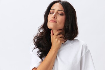 Woman sore throat and inflammation of the ligaments with a cold, a woman in a white t-shirt and jeans on a white background, copy space