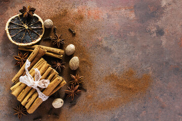 Christmas spices. Christmas composition with cinnamon sticks; anise stars, nutmeg, cloves, hazelnut and dried orange slices on dark background. Copy space for your text. Rustic vibe. - 551405538