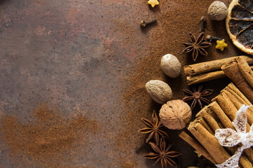 Christmas spices. Christmas composition with cinnamon sticks; anise stars, nutmeg, cloves, hazelnut and dried orange slices on dark background. Copy space for your text. Rustic vibe. - 551405557