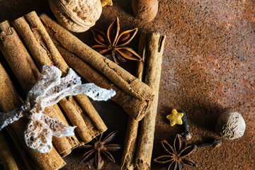 Christmas spices. Christmas composition with cinnamon sticks; anise stars, nutmeg, cloves, hazelnut and dried orange slices on dark background. Copy space for your text. Rustic vibe. - 551405580