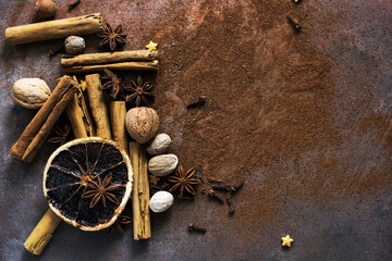 Christmas spices. Christmas composition with cinnamon sticks; anise stars, nutmeg, cloves, hazelnut and dried orange slices on dark background. Copy space for your text. Rustic vibe. - 551405798