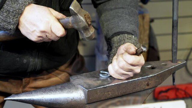 An adult blacksmith finishes making a miniature steel horseshoe for sale at fair