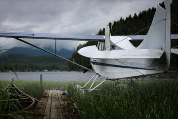 A generic seaplane without a brand or logo sits in a quiet lake on a stormy day in Alaska.  It is...