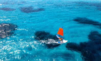 Aerial view of windsurfer on blue sea at sunny summer day. Windsurfing. Extreme sport and vacation....