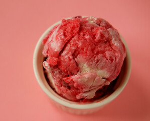 Bowl of pink strawberry ice cream and fresh berries isolated on pink background.