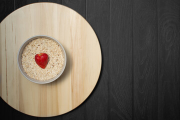 bowl of oatmeal with strawberry on white plate and black wooden background