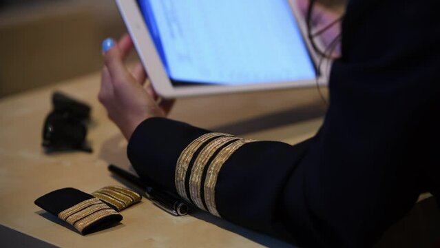 Unrecognizable female pilot preparing flight documentation on a tablet. Electronic flight bag. Selective focus
