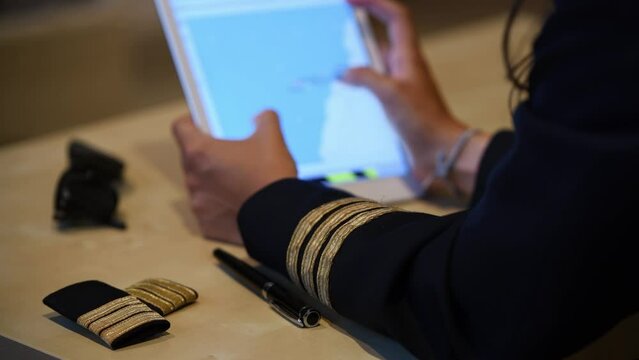 Unrecognizable female pilot preparing flight documentation on a tablet. Electronic flight bag. Selective focus
