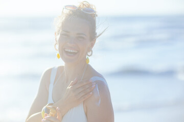 happy elegant woman in swimwear at beach applying sunscreen