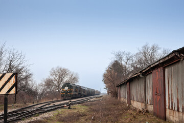 Freight train, a cargo train, on standby in Serbia, in the countryside of Vojvodina, at a rural train station, being pulled by an old diesel locomotive. ..