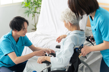高齢者を介護ベッドから車椅子に移乗させる介護士 - obrazy, fototapety, plakaty