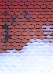 Some snow on a red tiled roof