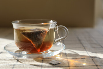 Tea bag in glass cup on table, closeup. Space for text