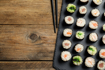 Tasty sushi rolls served on wooden table, flat lay. Space for text