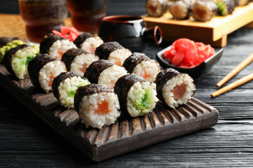 Tasty sushi rolls served on black wooden table
