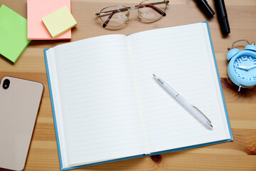 Empty notebook. smartphone, glasses and stationery on wooden table, flat lay